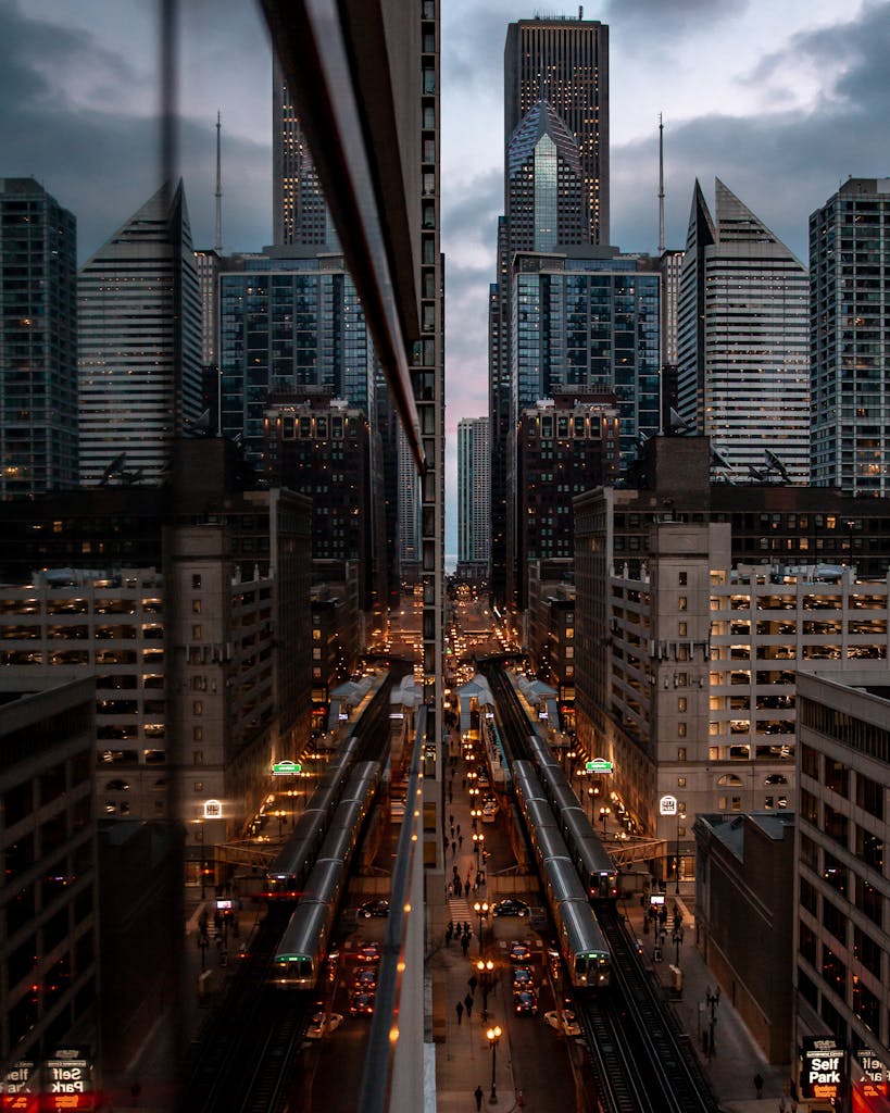 Urban cityscape of Chicago showcasing skyscraper reflections at dusk with busy streets and railway lines.